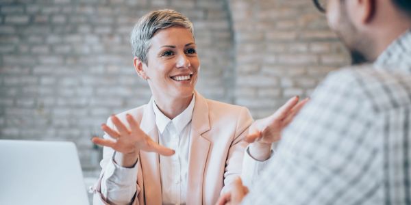Woman in a meeting smiling and talking with a colleague.