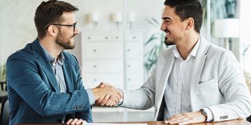 Two businessmen shaking hands at a meeting.