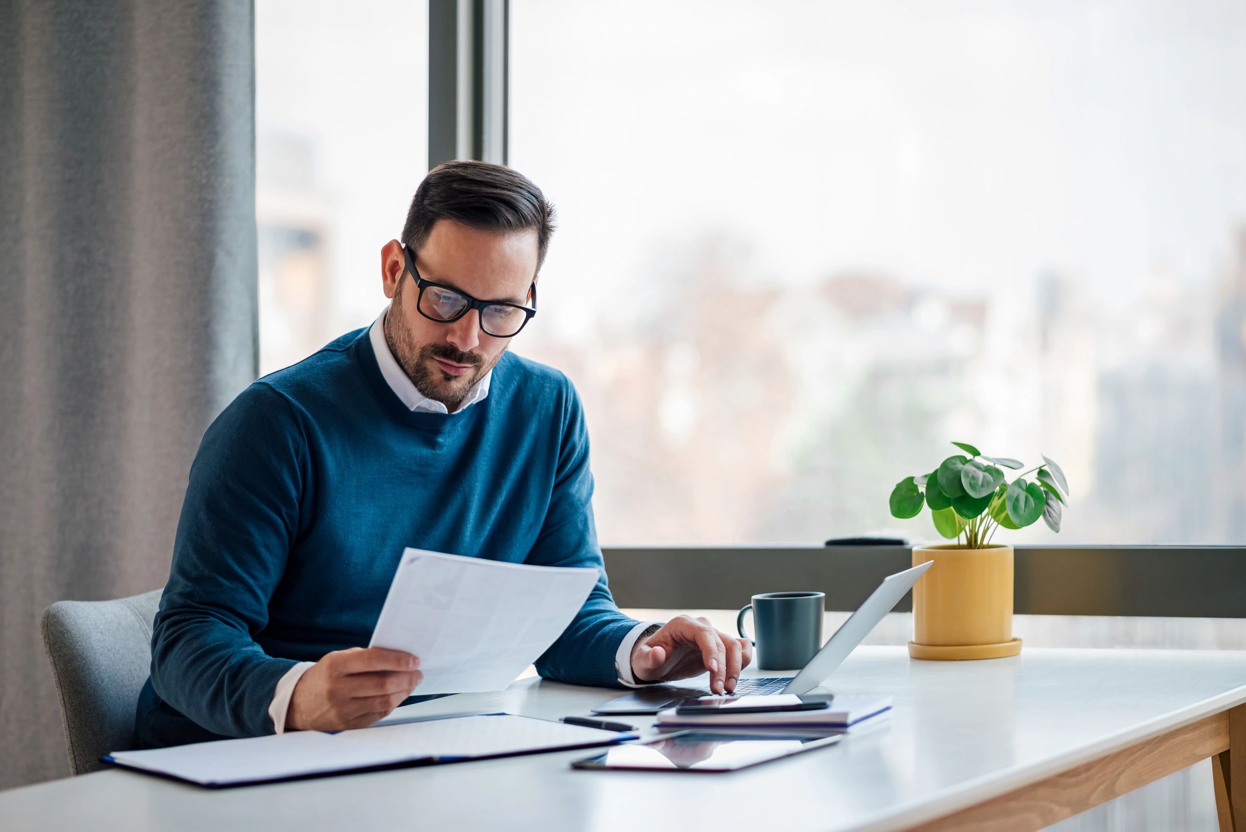 Small business owner reviewing financial documents at his desk.