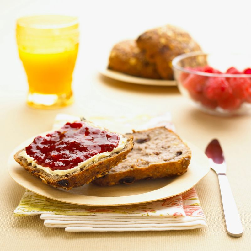 Breakfast with slices of bread topped with strawberry jam and orange juice