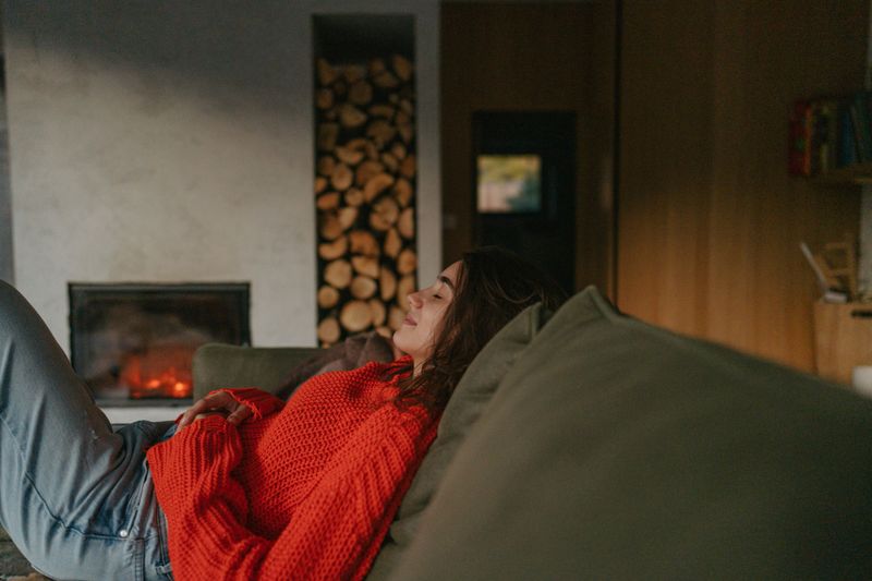 Portrait of a young woman in her living room; staying in her warm and cozy remote location home.