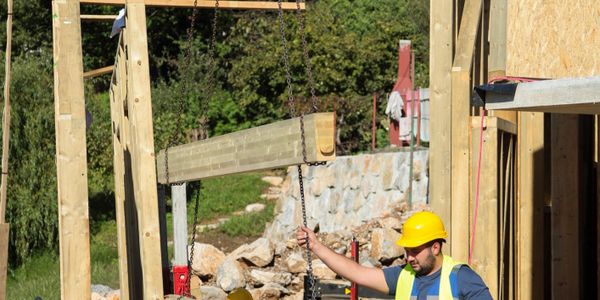 Two construction workers in helmets and vests discuss a building site.