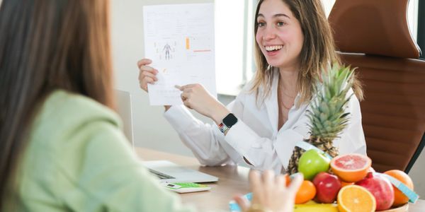 Nutritionist explaining a healthy diet with fresh fruits on the table to a client.