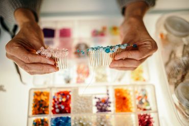 Hands holding beaded hair combs above a colorful bead organizer.