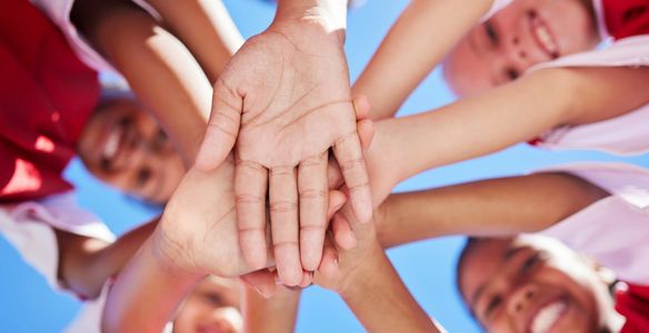 Group of people stacking hands in a circle.