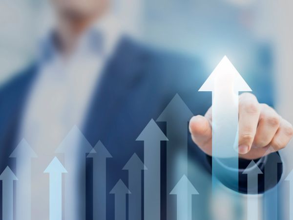 Businessman pointing at upward arrows indicating growth and progress.