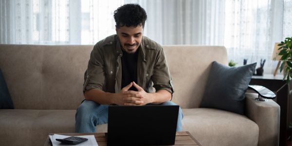 Man sitting on sofa using laptop.