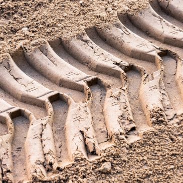 Heavy machinery tire tracks in dirt.