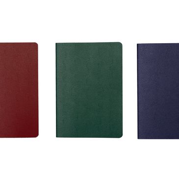 Three closed notebooks in red, green, and blue colors.