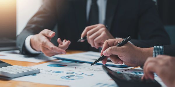 Close-up of business professionals discussing financial charts and using a calculator.