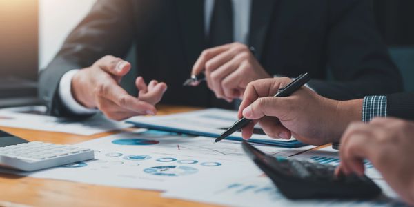 Close-up of business professionals discussing financial charts and using a calculator.
