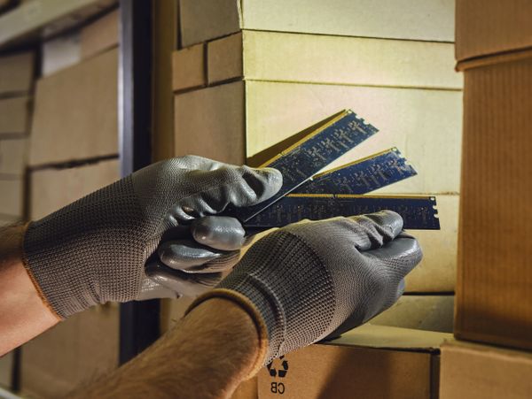 Person wearing gloves handling electronic circuit boards in storage.