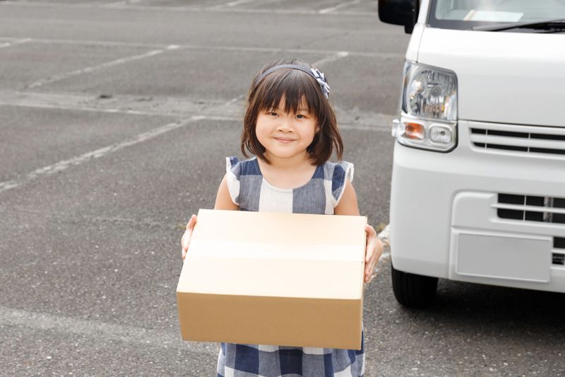 Smiling child receiving parcel from courier. An image of receiving support and gifts.