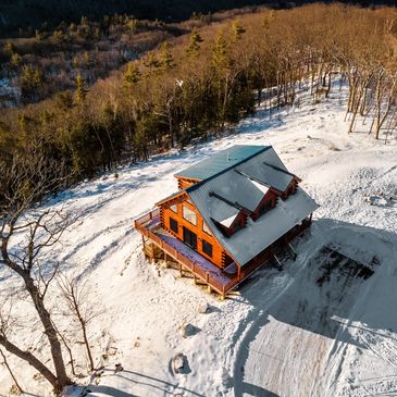 Aerial drone photo of a snowy Vermont log cabin and mountain landscape by an FAA-certified pilot.