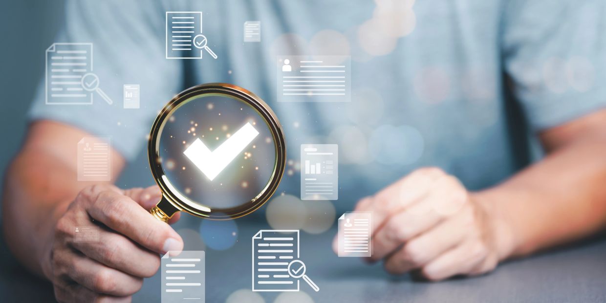 Person holding magnifying glass with checkmark, symbolizing document verification.