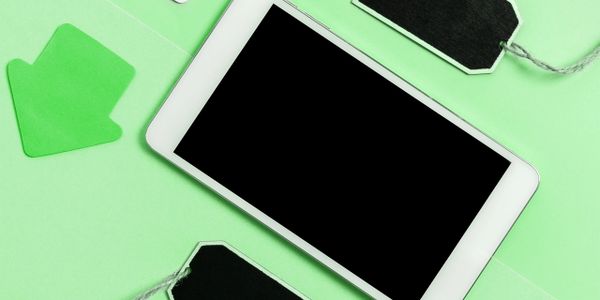 Tablet with blank screen surrounded by black tags and green arrow on green background.