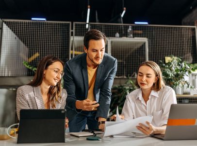 Three coworkers discussing documents in an office.