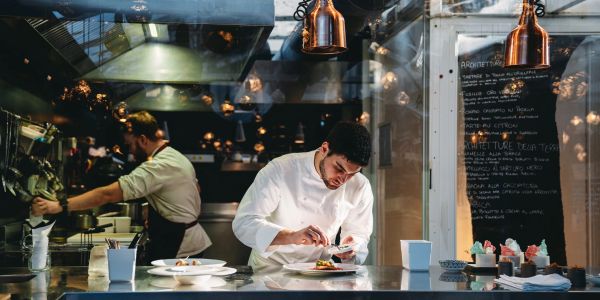 Chef concentré dressant un plat en cuisine.