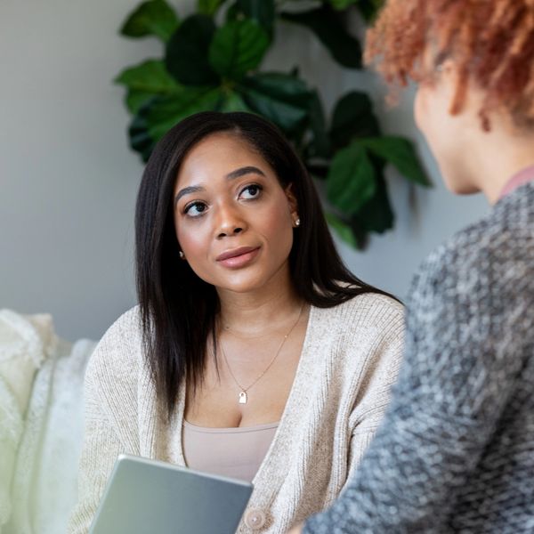 Two women engaged in a thoughtful conversation indoors.