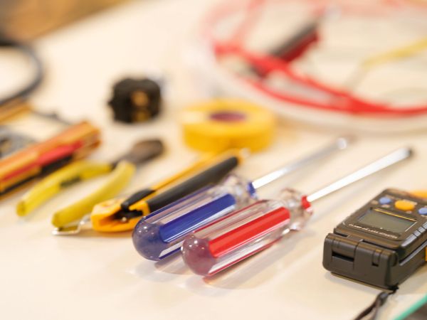 Various hand tools hanging on a perforated metal board in a workshop.