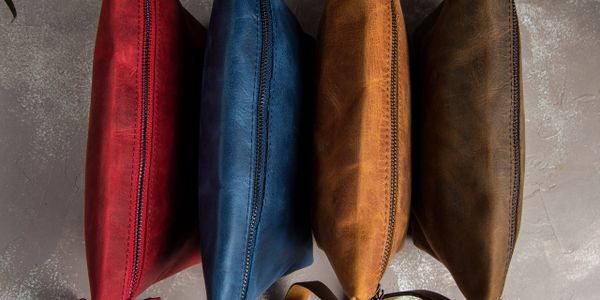 Four colorful leather pouches with zippers arranged vertically.