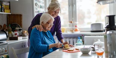 Caregiver assisting senior woman with her meal in a comfortable home setting.