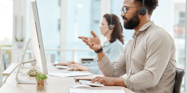 Two customer support agents working with headsets at computers.
