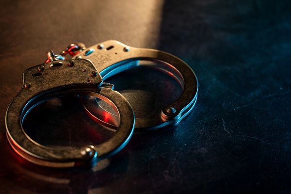 Metal handcuffs on a dark textured surface with dramatic lighting.