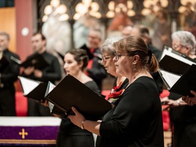 Choir members singing in a church setting during a performance.