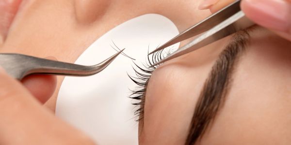 Applying eyelash extensions with tweezers.