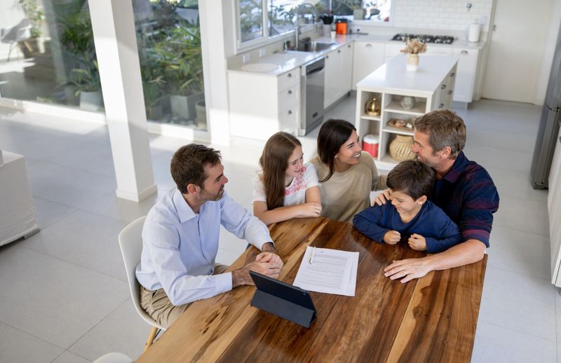 Happy family buying a house and talking to the real estate agent indoors - home ownership concepts