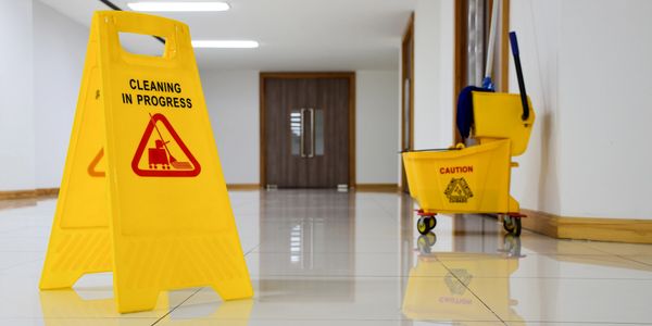 Yellow cleaning signs and mop bucket in a spotless hallway.