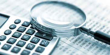 Magnifying glass on a calculator and some financial sheets.