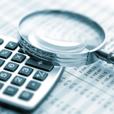 Magnifying glass on calculator and financial documents.