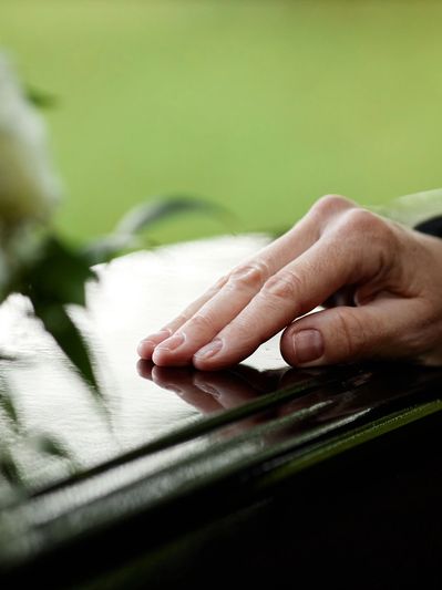 A hand gently resting on a polished surface, symbolizing grief.