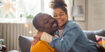 Father and daughter hugging joyfully at home.