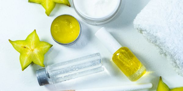 Skincare products with starfruit and towel on white surface.
