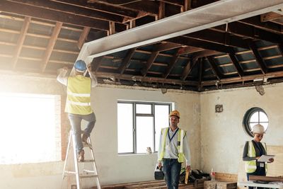 Construction workers renovating a room with tools and safety gear.