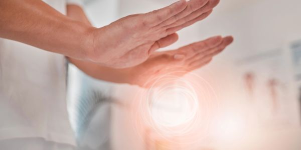 Person showing hands in a calm, healing gesture with light effect.