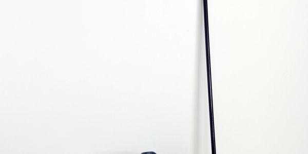 Modern black floor lamp with a round base against a white wall.
