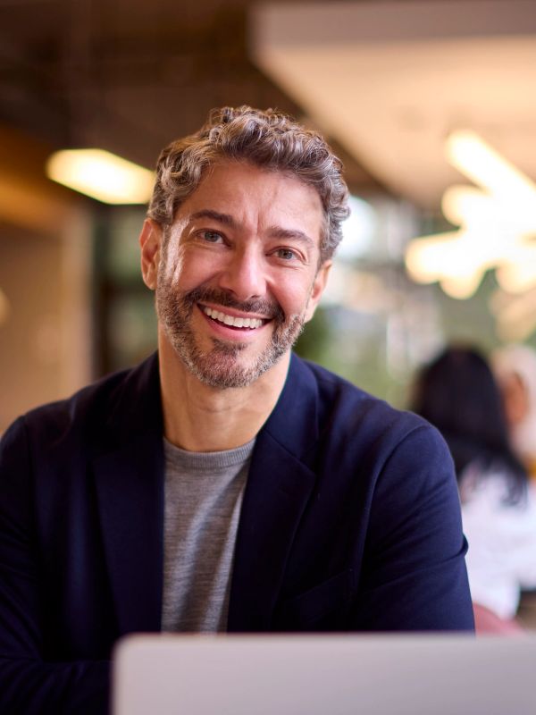 Smiling man with curly hair and beard indoors.
