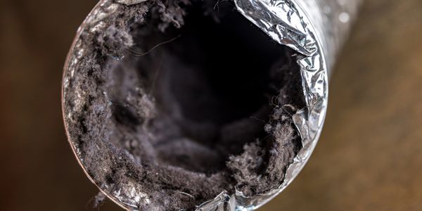 Close-up of a dirty, dust-filled air duct.
