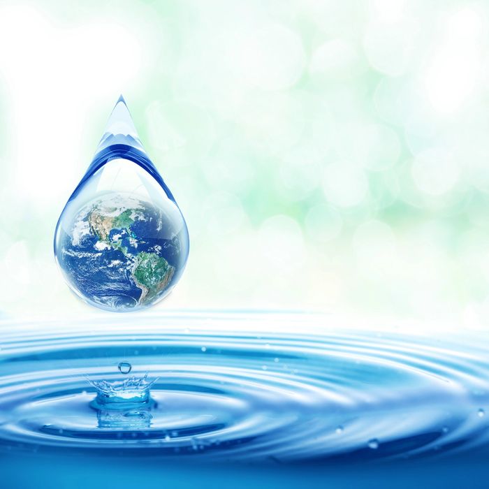 A water droplet containing Earth hovers above rippling water.