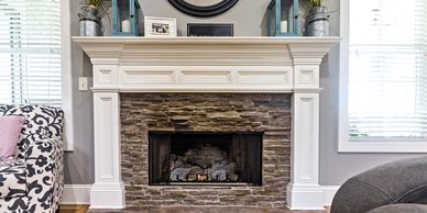 Elegant stone fireplace with white mantel and decorative accents in a cozy living room.