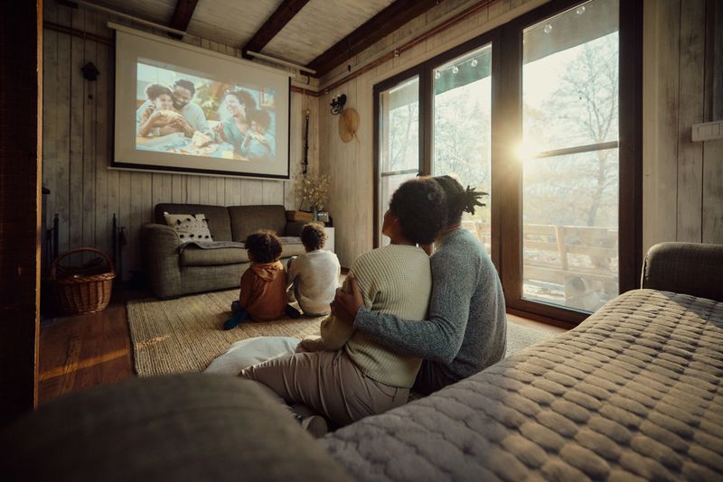 Rear view of relaxed African American family watching a movie in the living room.