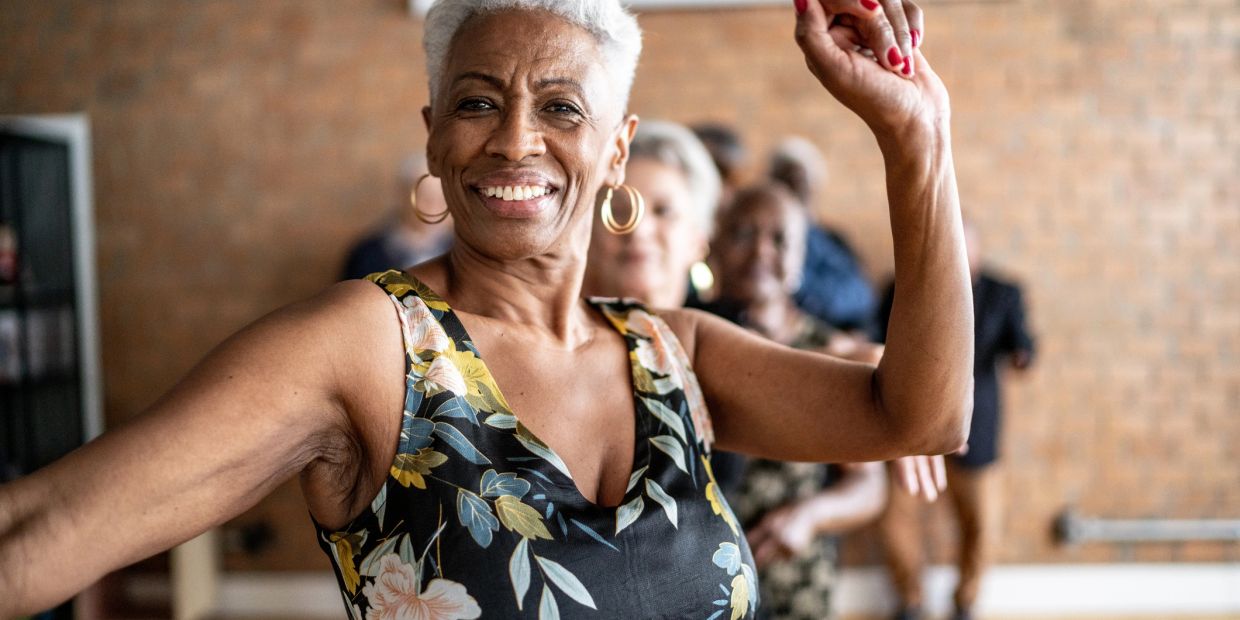 Smiling elderly woman dancing in a group.
