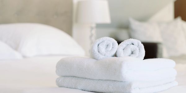 Neatly folded white towels on a bed in a cozy bedroom.