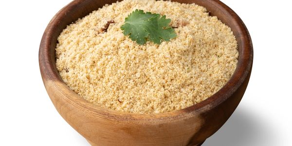 Wooden bowl filled with farofa topped with a cilantro leaf.