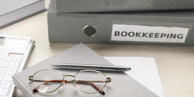A bookkeeping folder with pen and glasses.