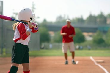 Young softball player preparing to bat during a game.